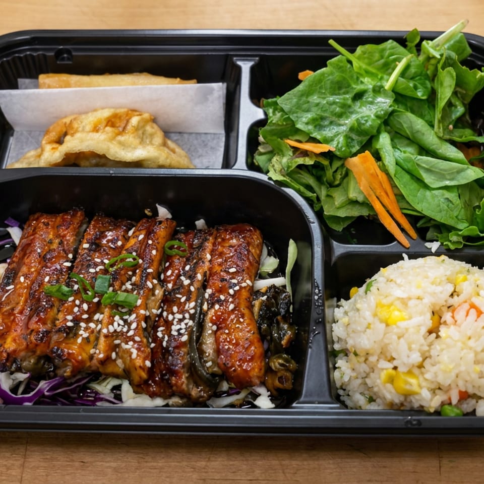 Bento box with glazed teriyaki meat, fried dumpling, green salad, and vegetable fried rice on a wooden table.