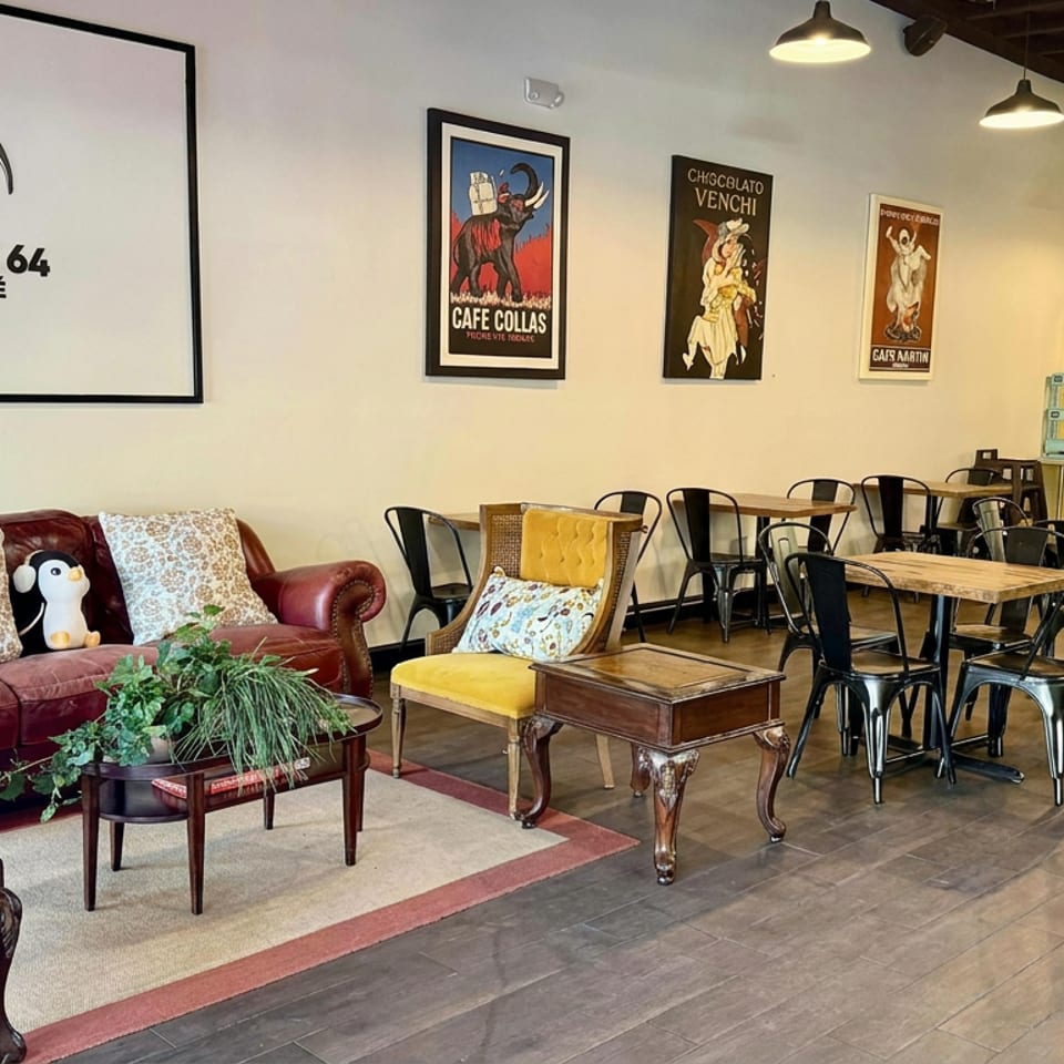 Penguin 64 Boba Café interior with vintage seating, wooden tables, black chairs, pendant lights, artwork, and counter area.